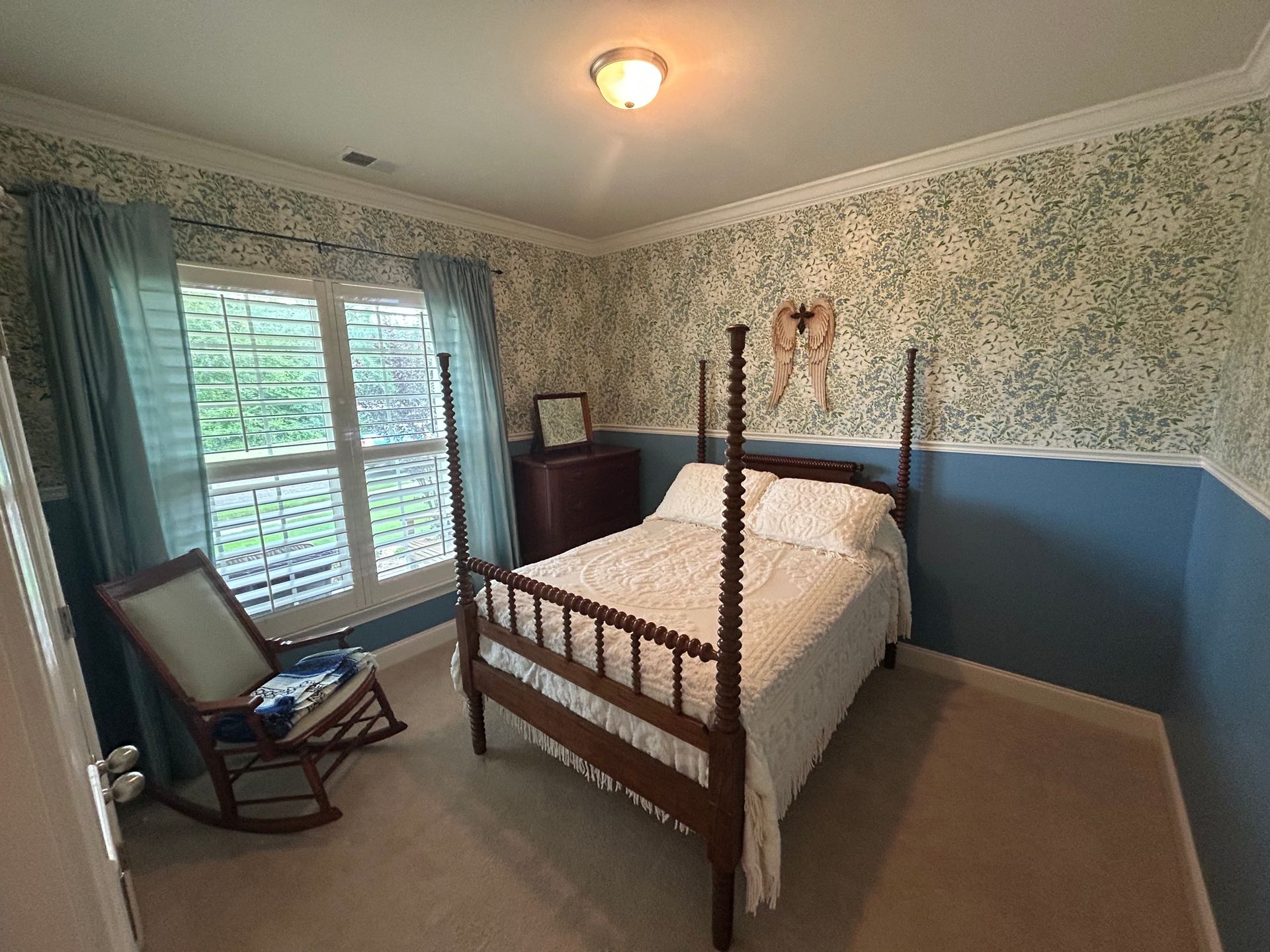 Bedroom with dark blue walls, a bed, hanging pendant lights, and a wooden nightstand.