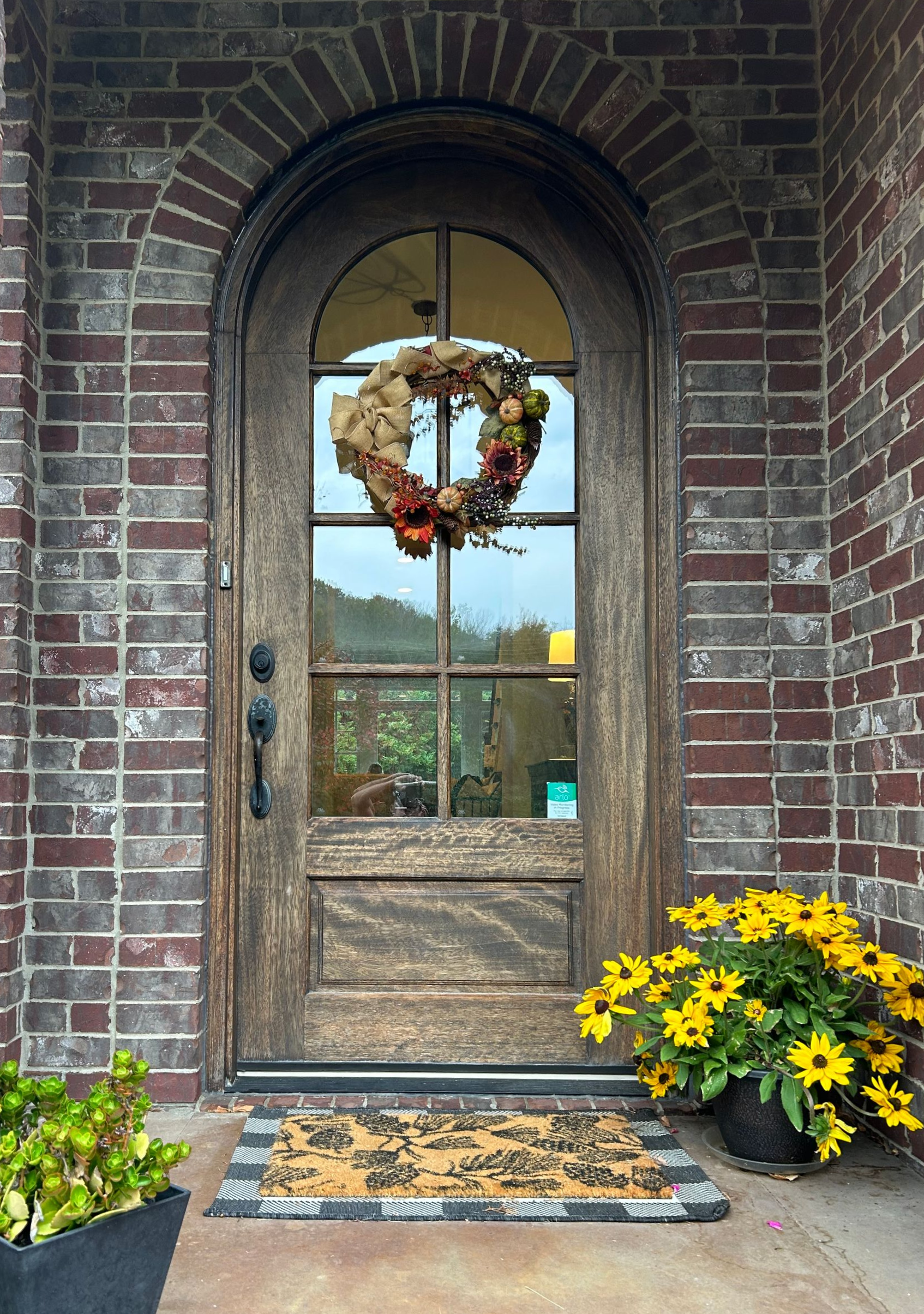 Wooden double front doors with glass panes, centered in a brick entryway