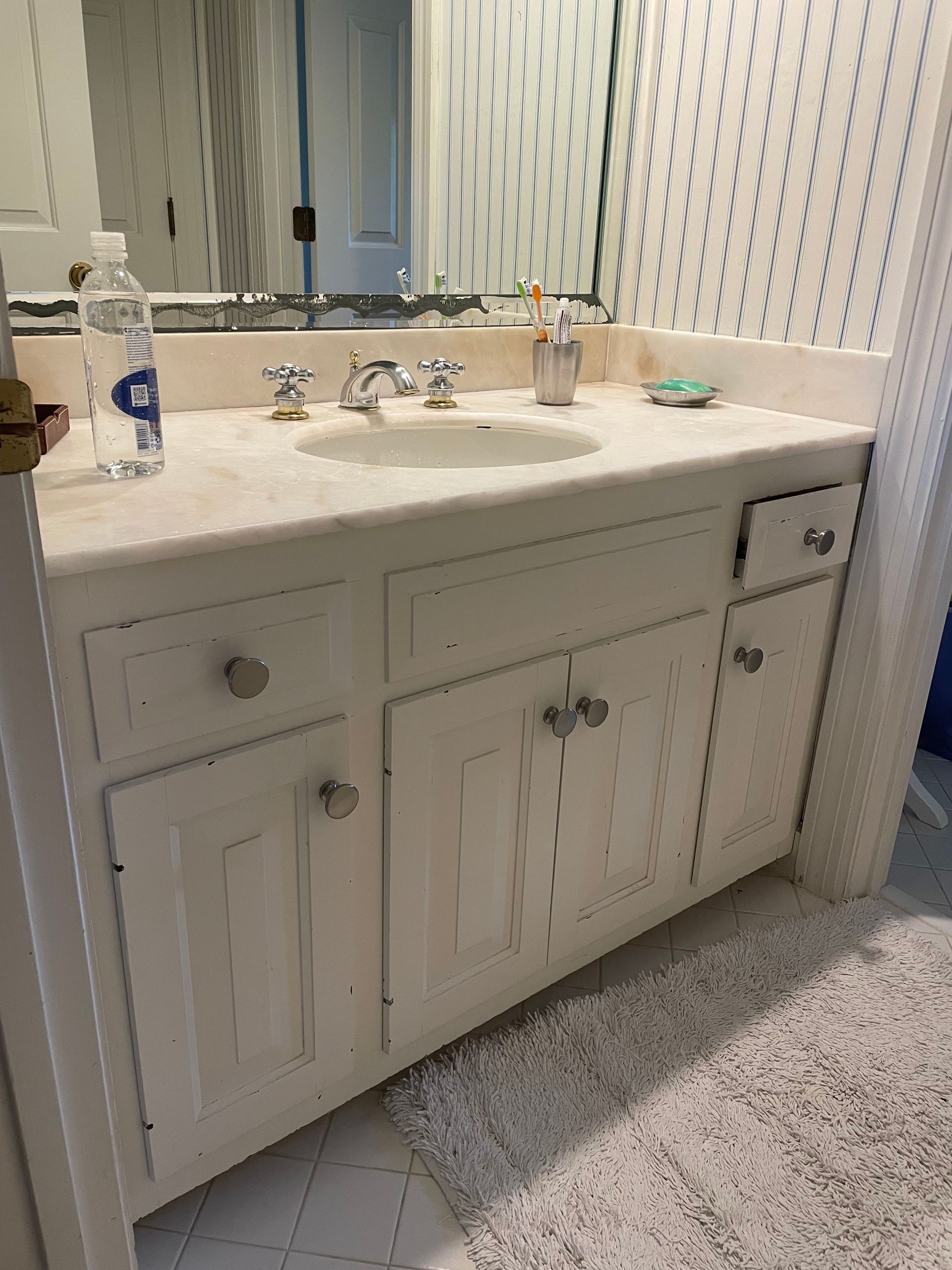 Blue floral bathroom with a corner tub, red flowers, and a vanity with mirror in an adjoining room