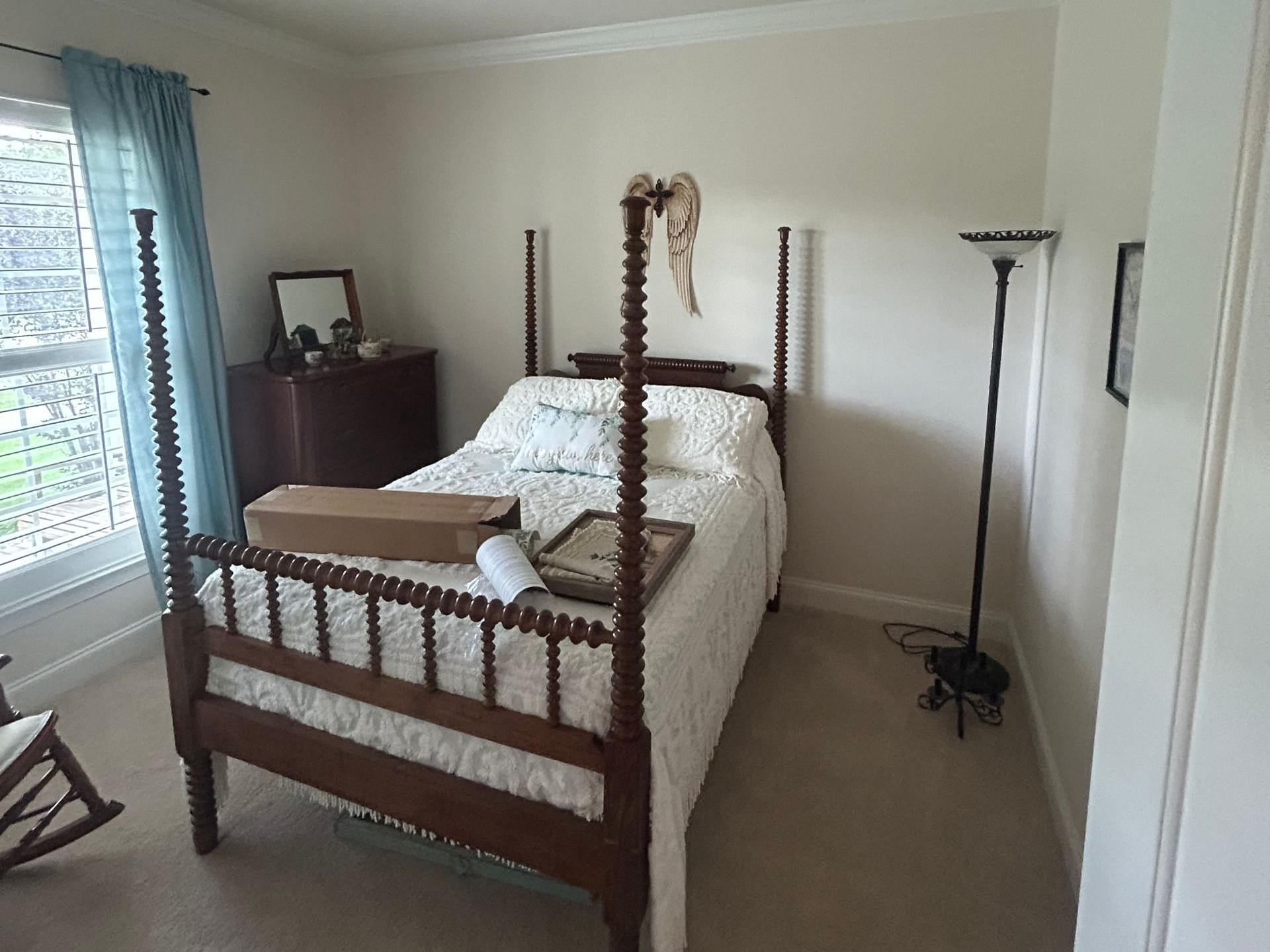 Bedroom with a bed, dresser, lamp, green walls, and framed photos above the headboard.