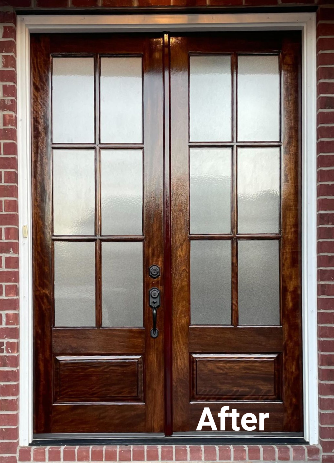 A set of dark-stained wooden double doors with six glass panes each and a white frame, set in a brick exterior wall.