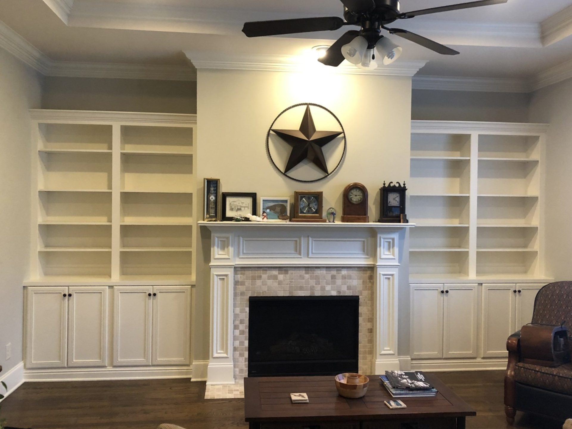 Living room with built-in white shelves, a white fireplace, and a large black star wall decoration
