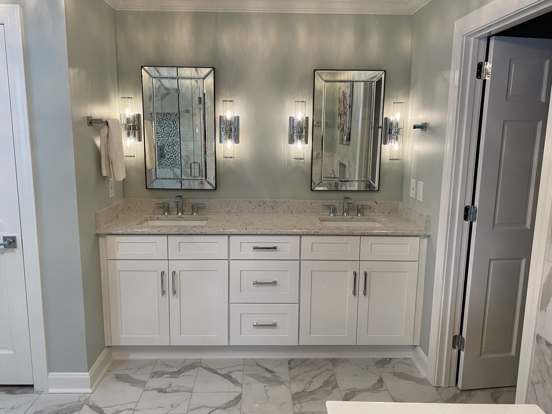 Double vanity bathroom with white cabinets, large mirrors, and gray walls in a bright, modern interior