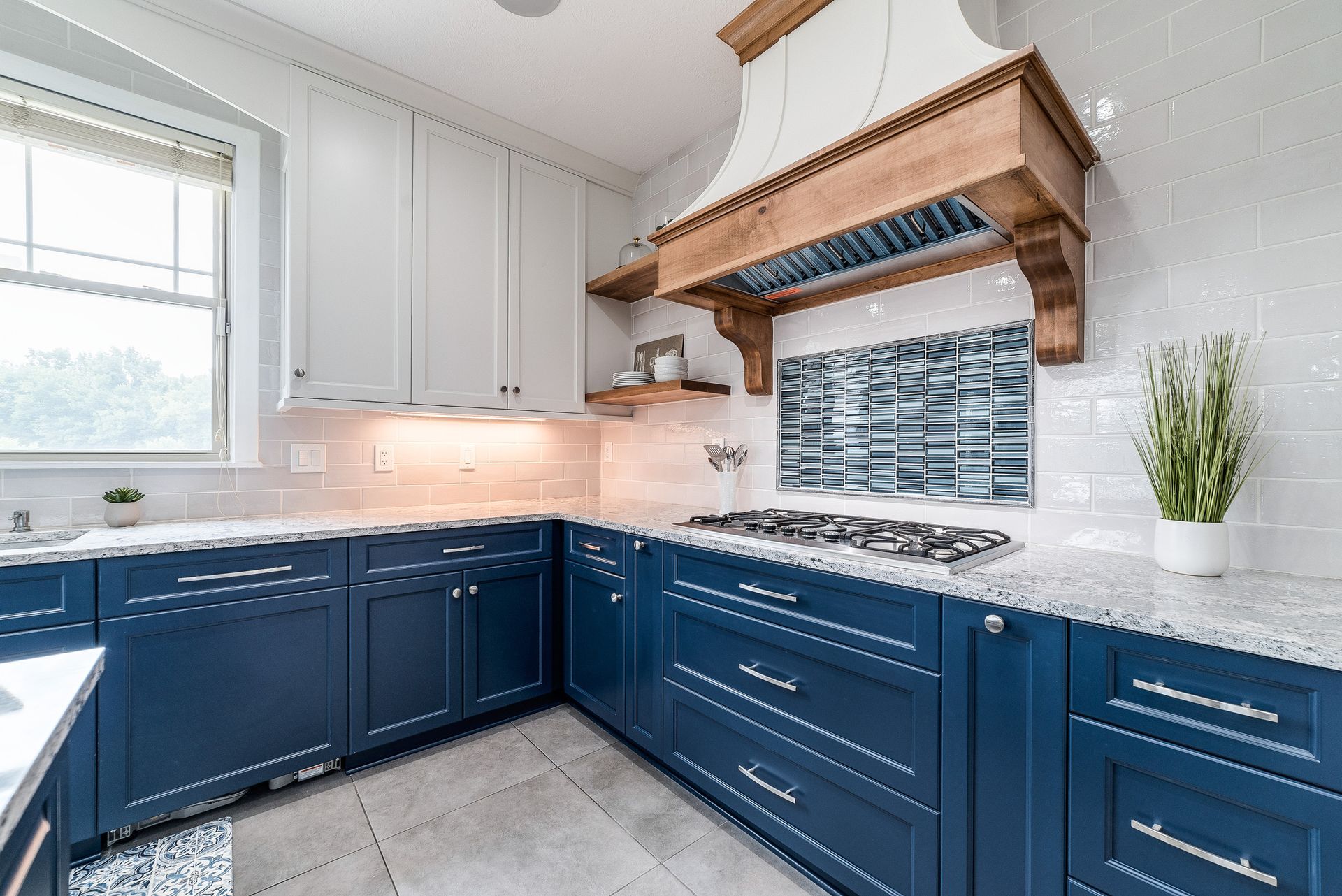 Modern kitchen with blue lower cabinets, white upper cabinets, and wood range hood