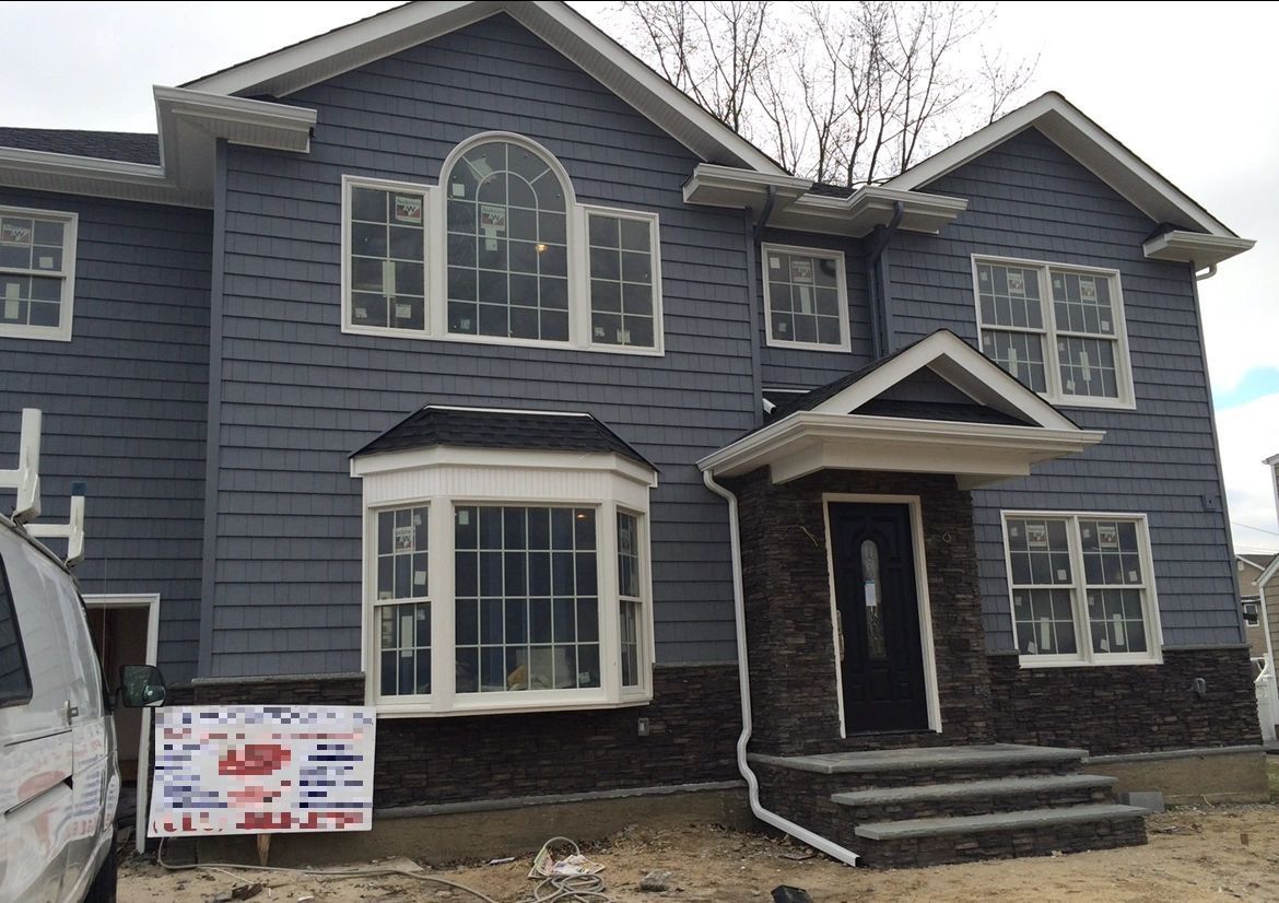 A large gray house with a white van parked in front of it