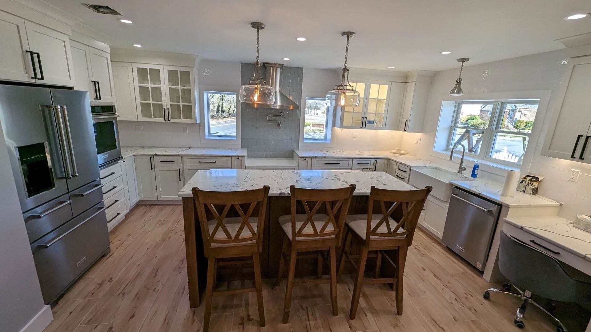 A kitchen with white cabinets , stainless steel appliances , and a large island.