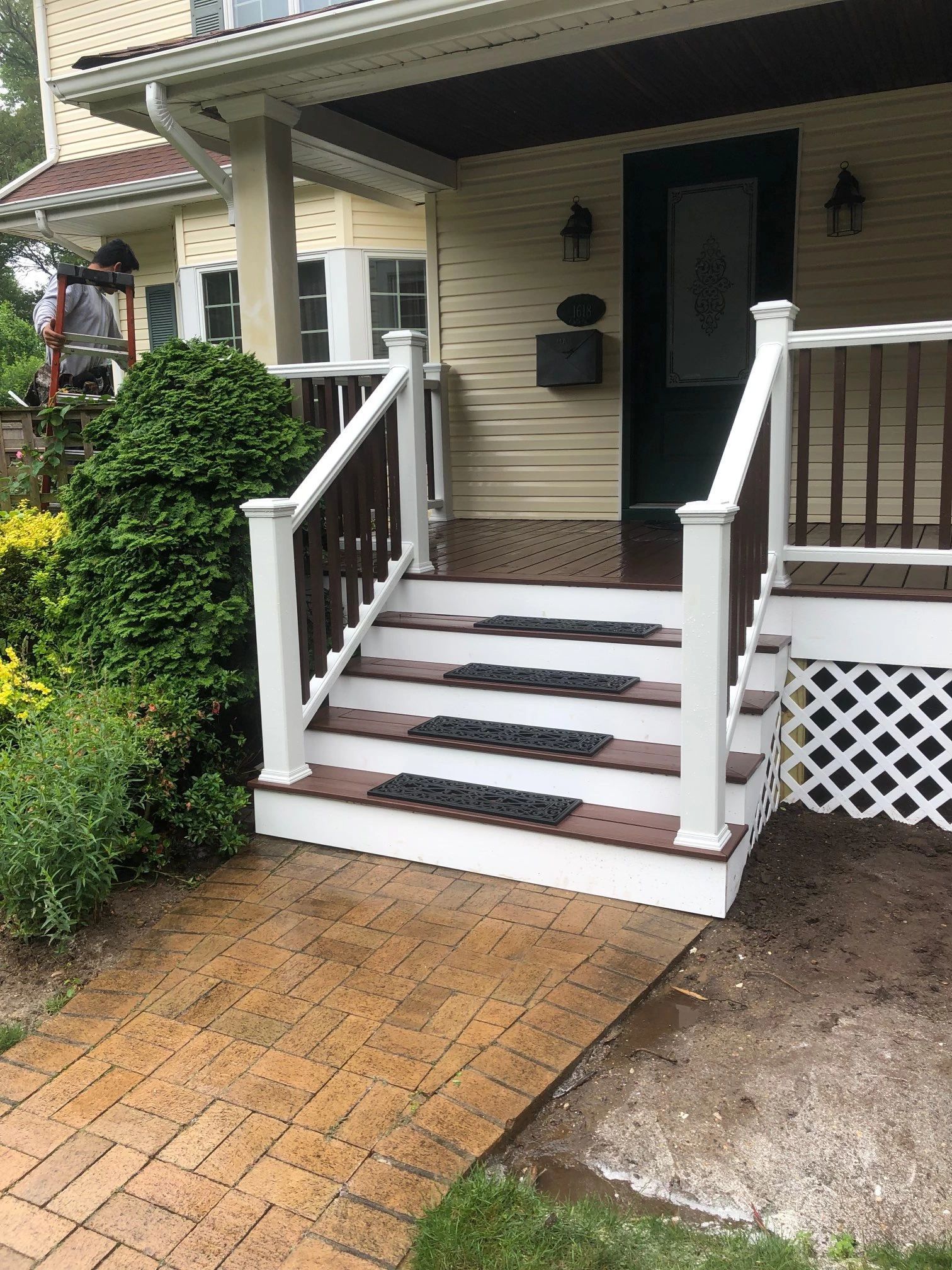 The front porch of a house with stairs and a white railing.