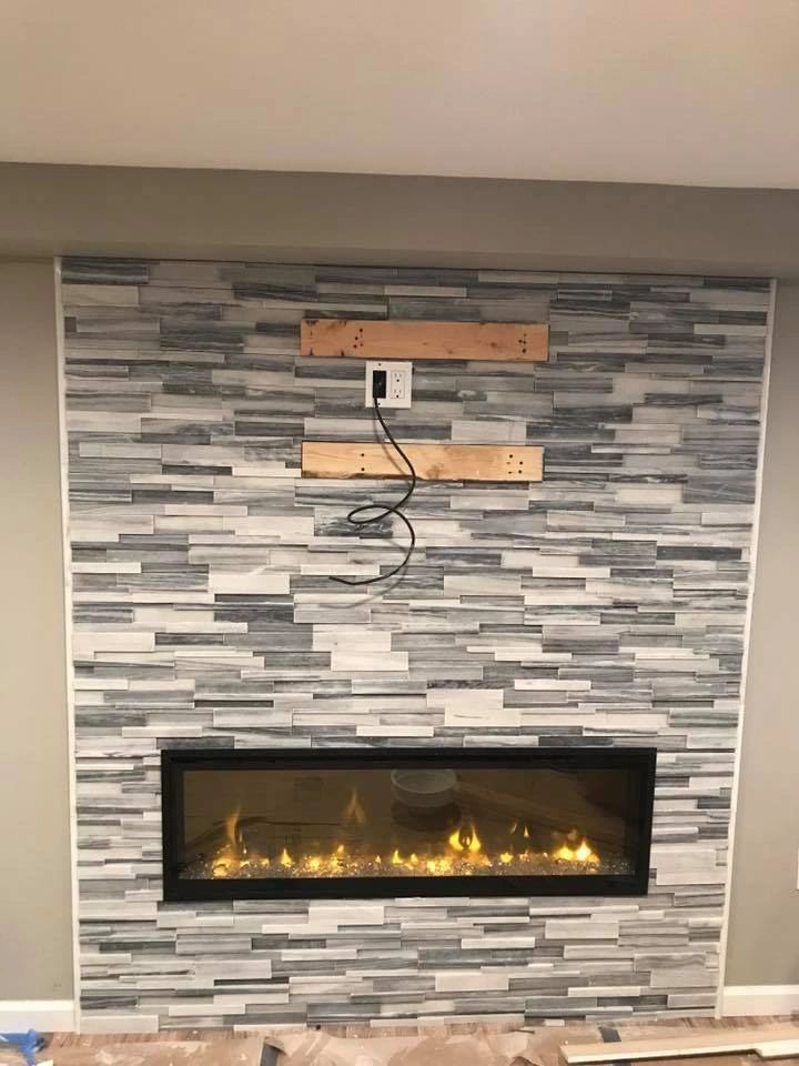 A fireplace is being installed in a living room with a brick wall.