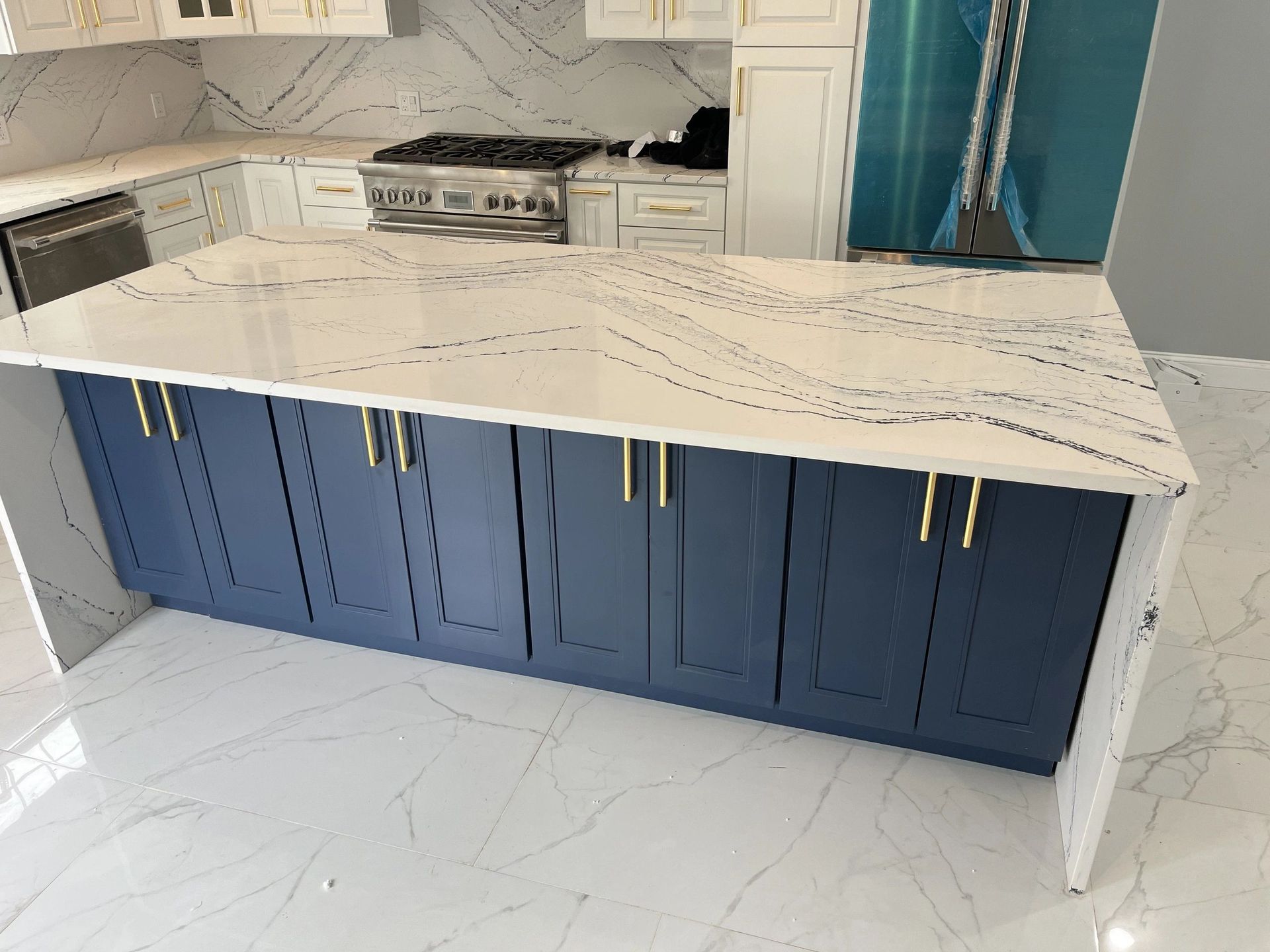 A kitchen with blue cabinets and white counter tops.