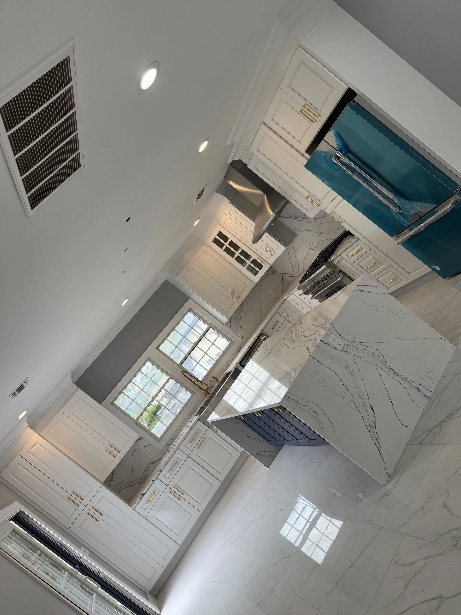 A kitchen with white cabinets and a blue refrigerator.