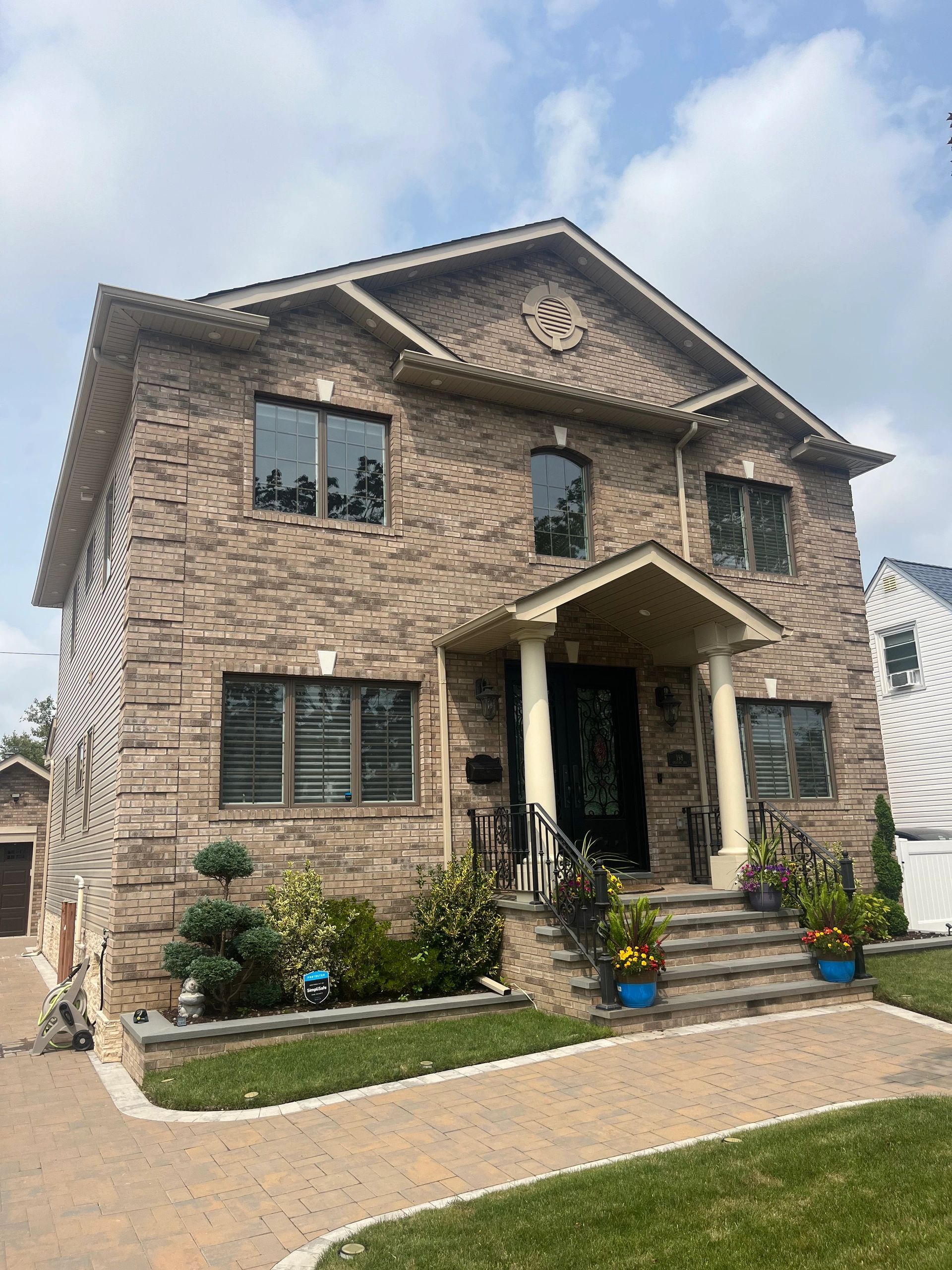 A large brick house with a lush green lawn in front of it.