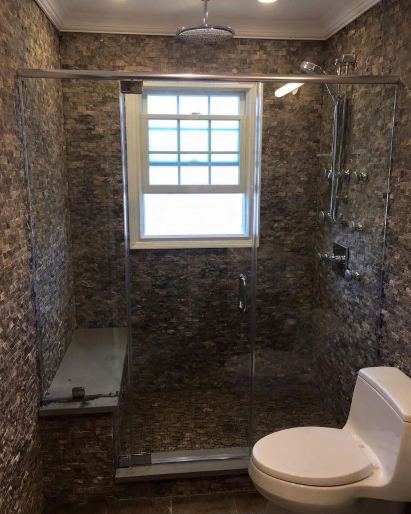 A bathroom with a toilet , shower and window.