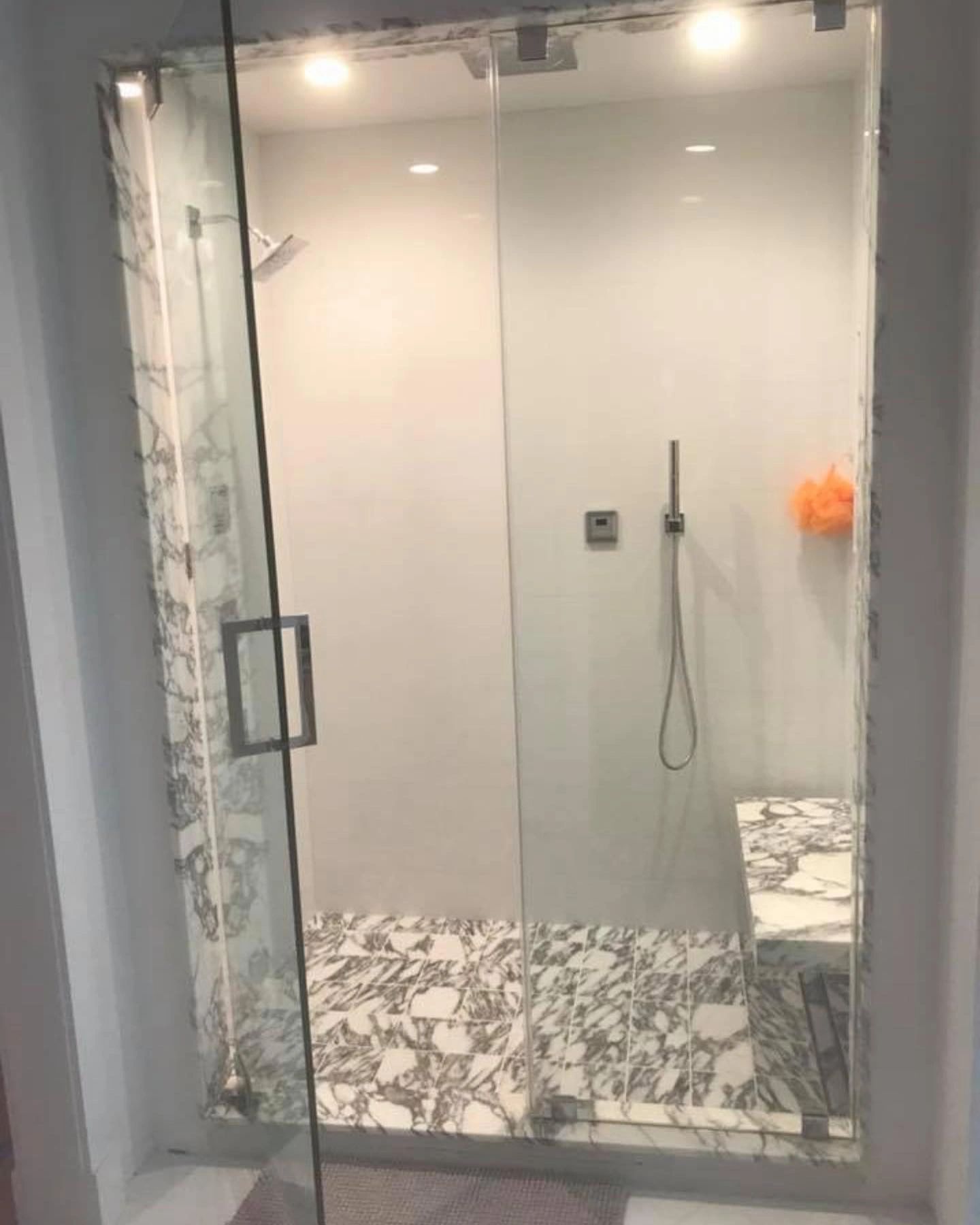 A bathroom with a walk in shower with a glass door.