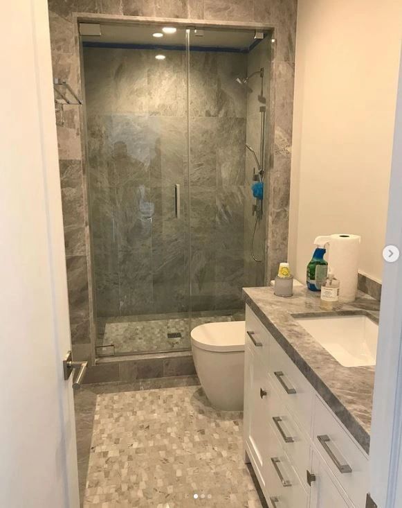 A bathroom with a toilet , sink , shower and glass door.