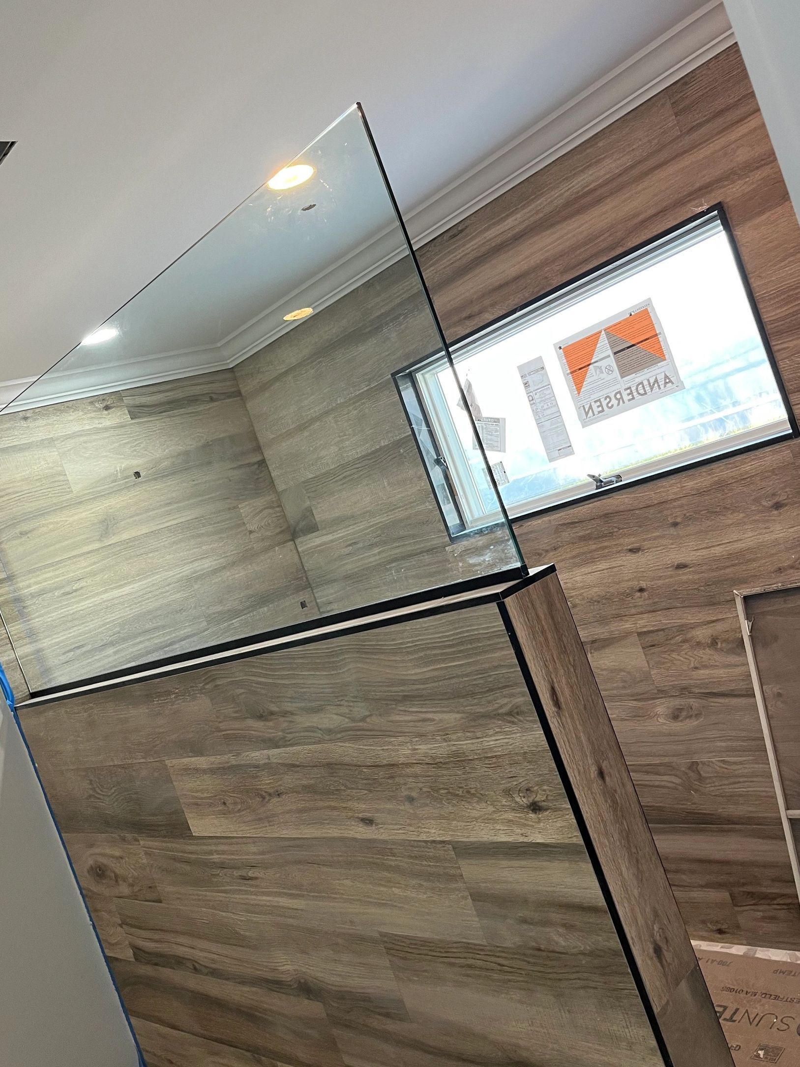 A bathroom with a glass shower door and a wooden wall.