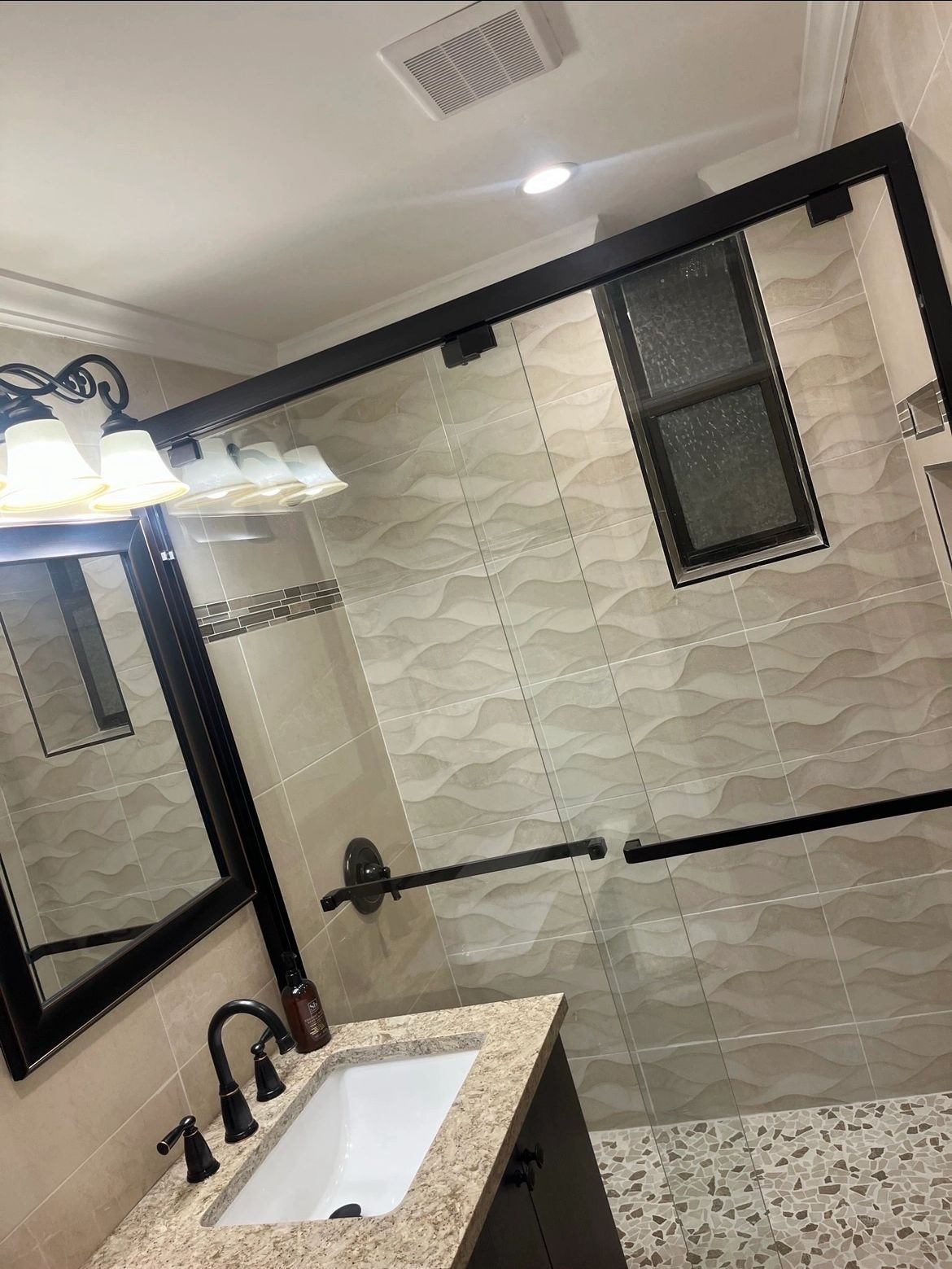 A bathroom with a sink , mirror , and sliding glass shower door.