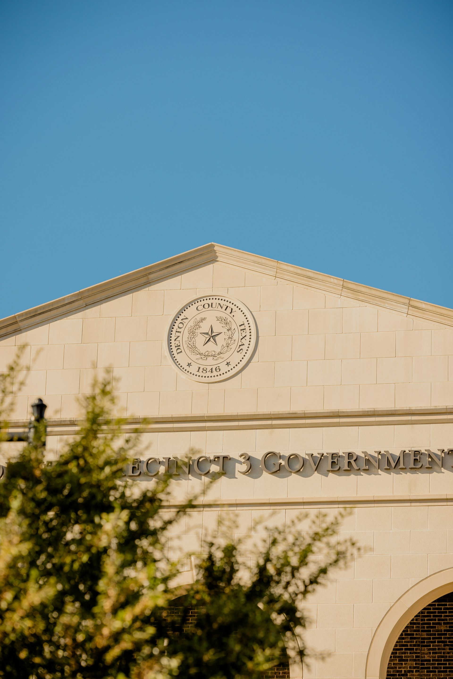 Tan stone building facade with circle emblem and the text