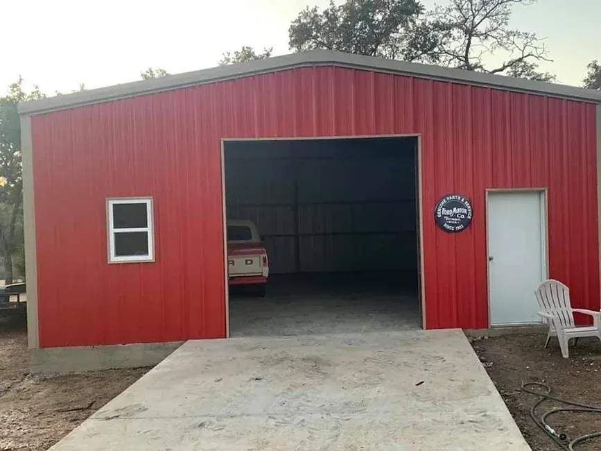 A red garage with a truck parked inside of it.