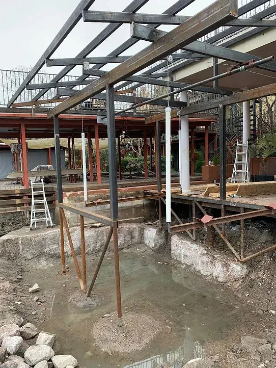 A building under construction with a metal structure and a ladder.