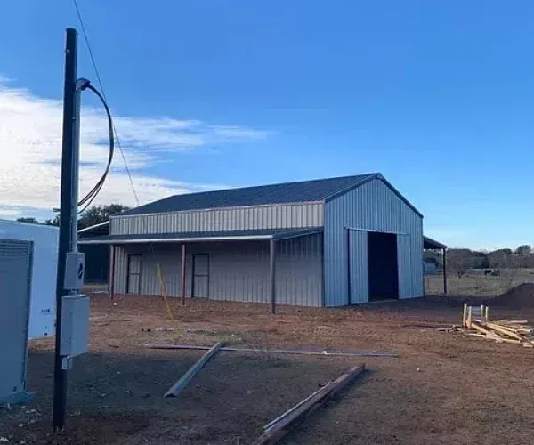 A large metal building is being built in the middle of a dirt field.