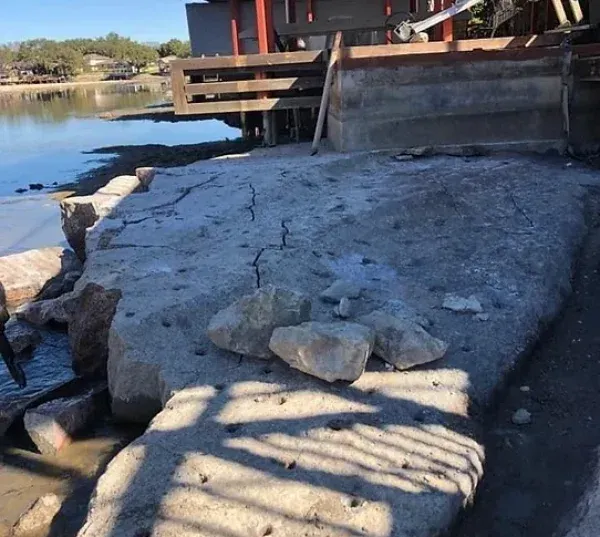A large rock is sitting next to a body of water.