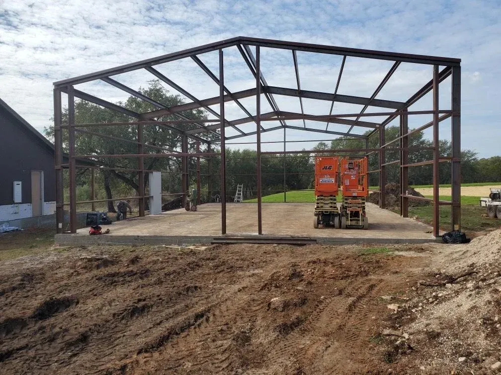 A large metal structure is being built in a dirt field.