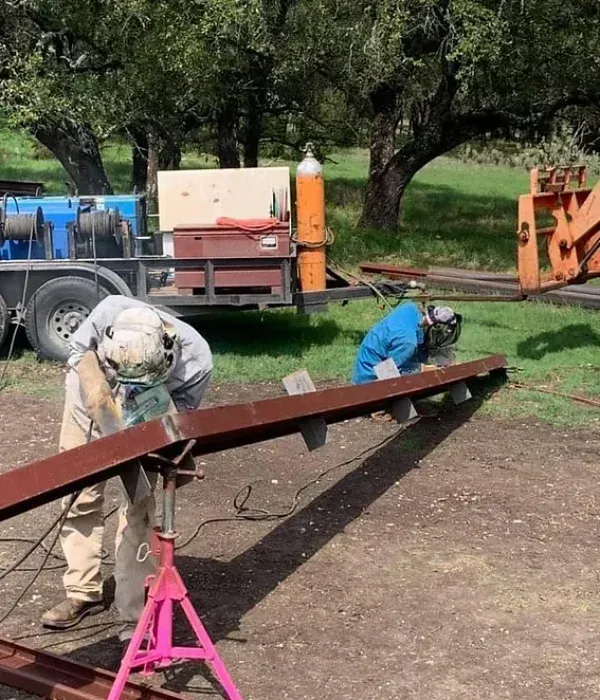 A man is welding a piece of metal in a field