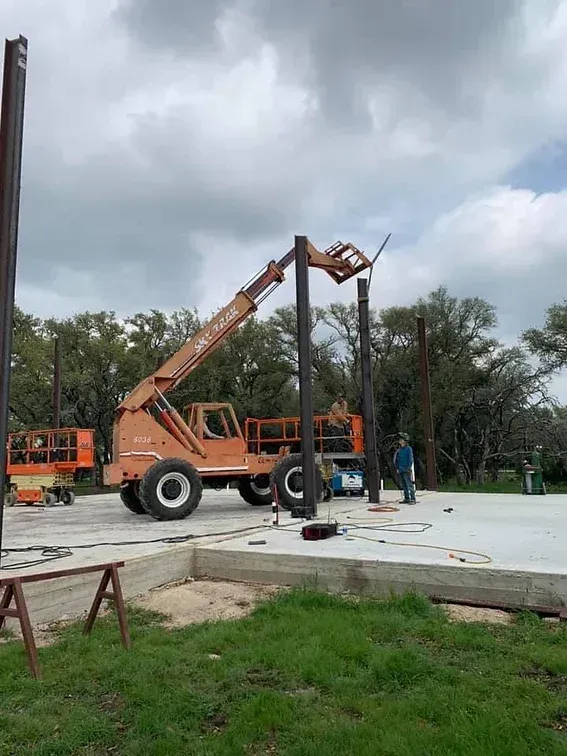 A crane is lifting a metal pole on a construction site.