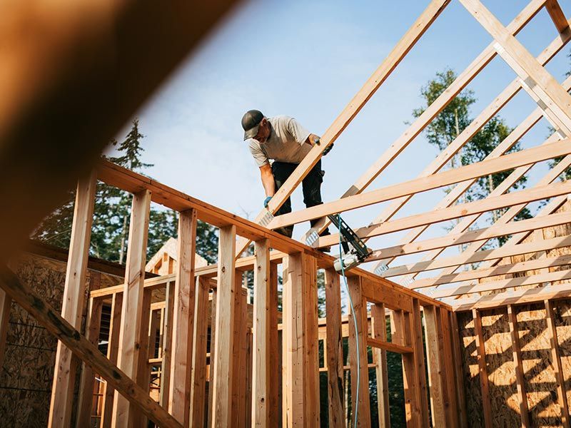 A man is working on the roof of a house under construction. A man is working on the roof of a house under construction.