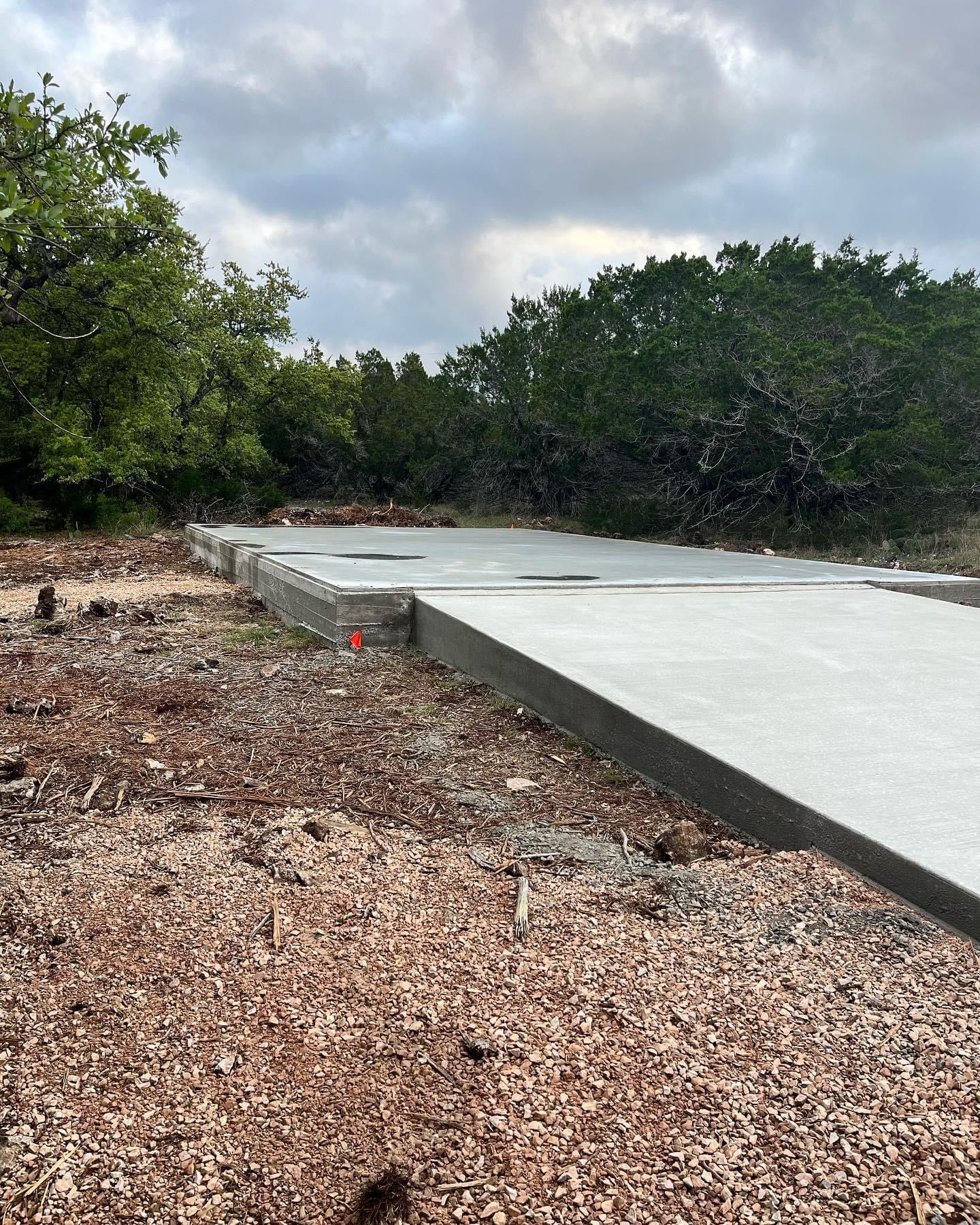 A concrete walkway is being built in a field with trees in the background.