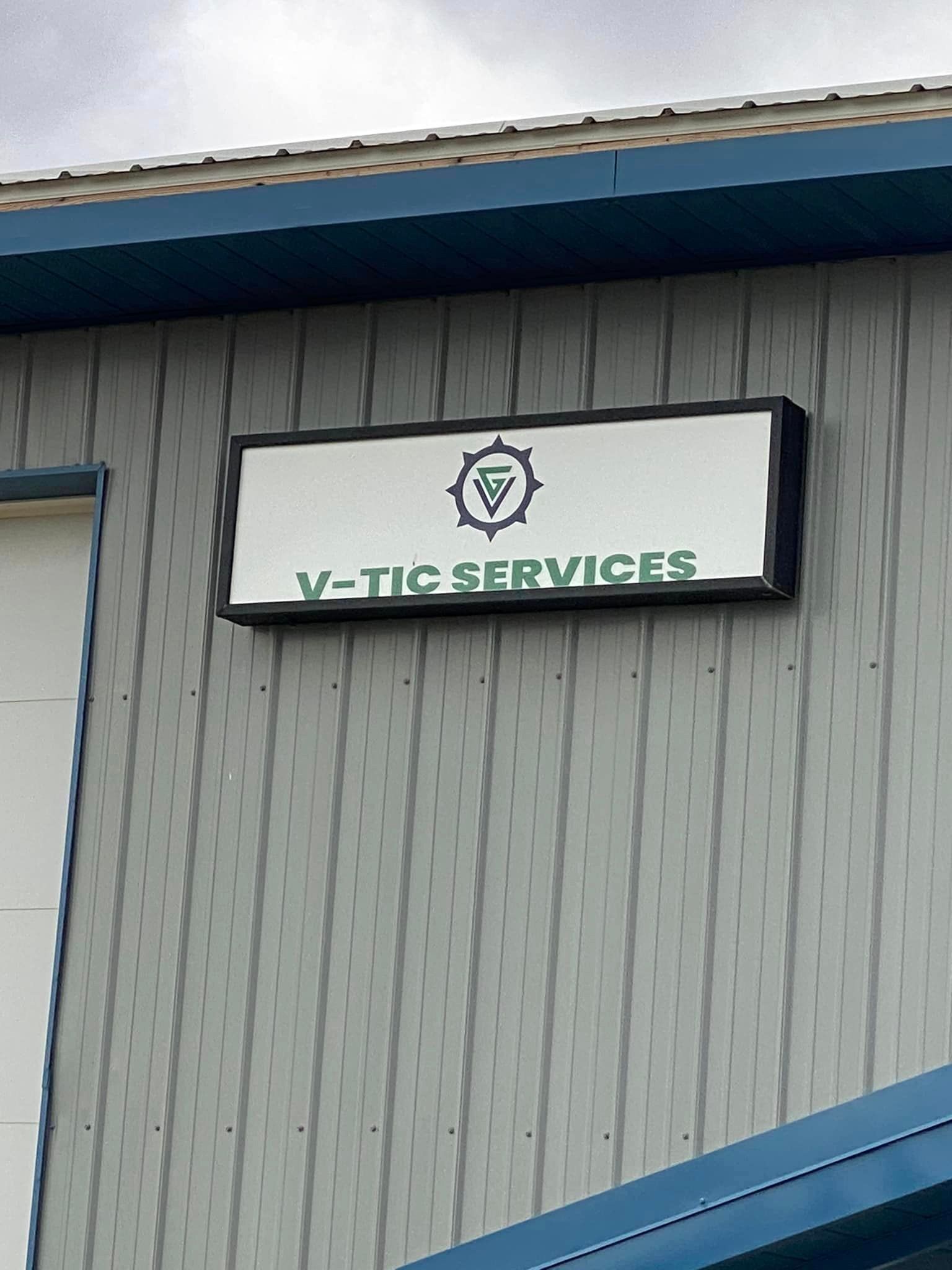 A sign on the side of a building says v-tec services