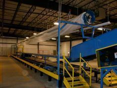 A conveyor belt in a warehouse with stairs leading up to it.