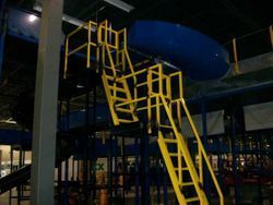 A playground with stairs and a slide in a building at night.