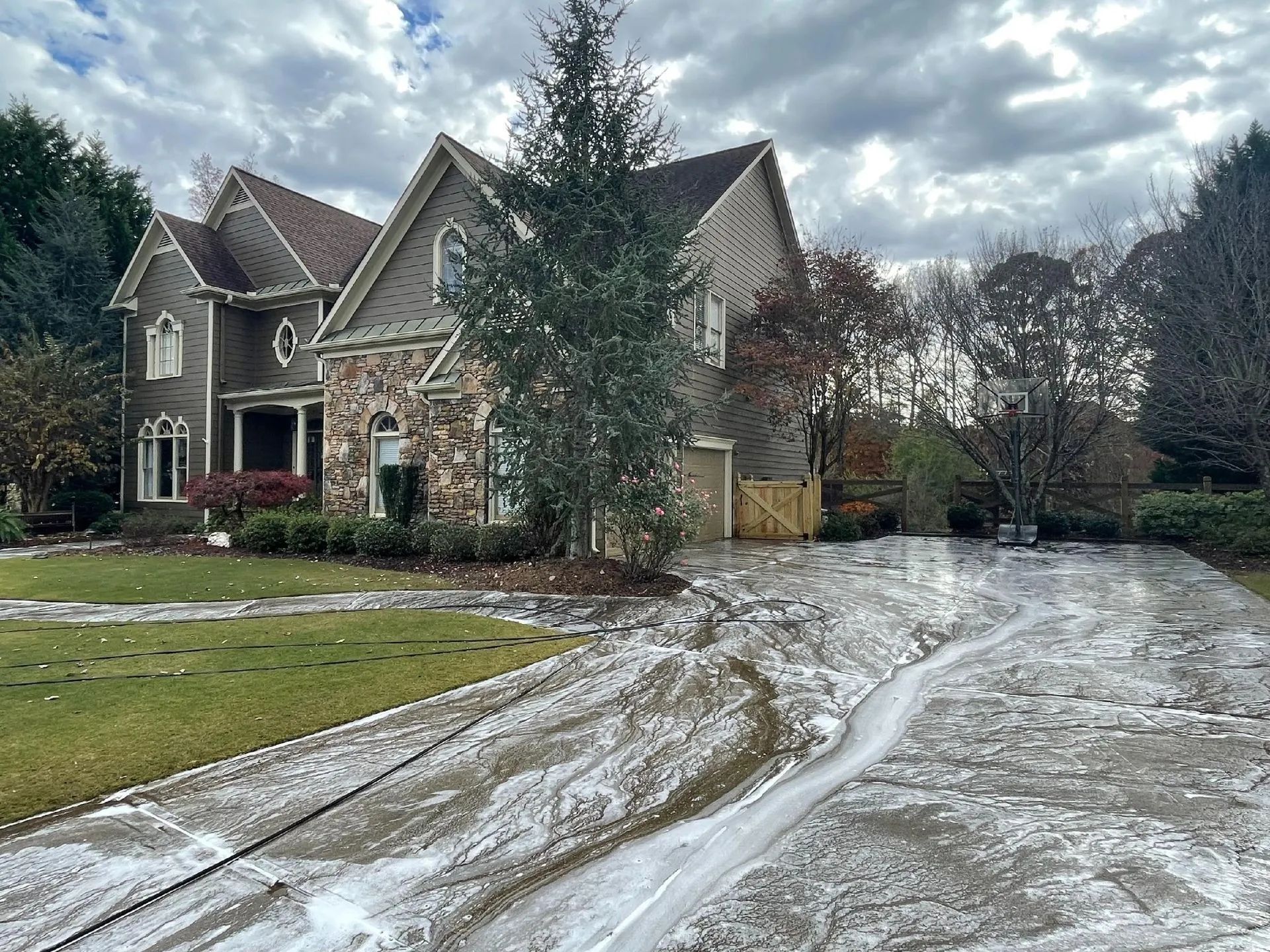 Two-story house with stone and siding facade, soap-covered driveway, overcast sky.