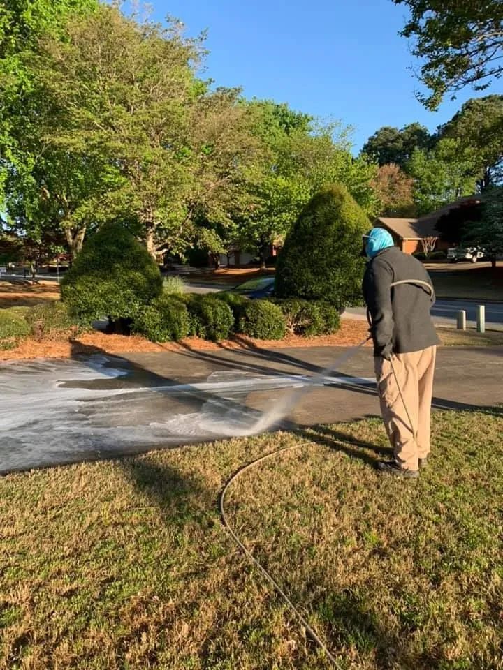 Person spraying a foamy substance on a driveway, wearing a mask and protective clothing.
Outdoors, 