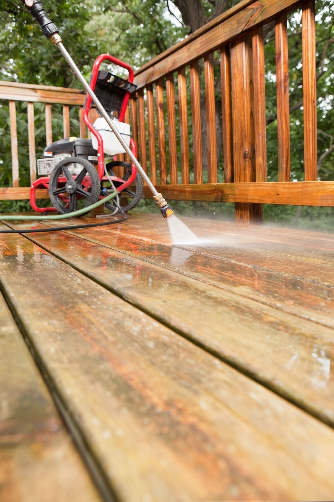 A man is cleaning the roof of a house with a high pressure washer.