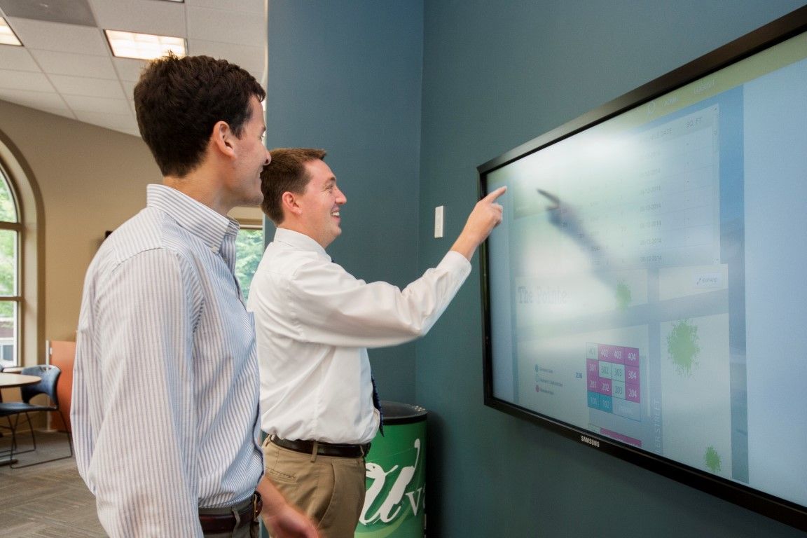 Two men are looking at a large flat screen tv.