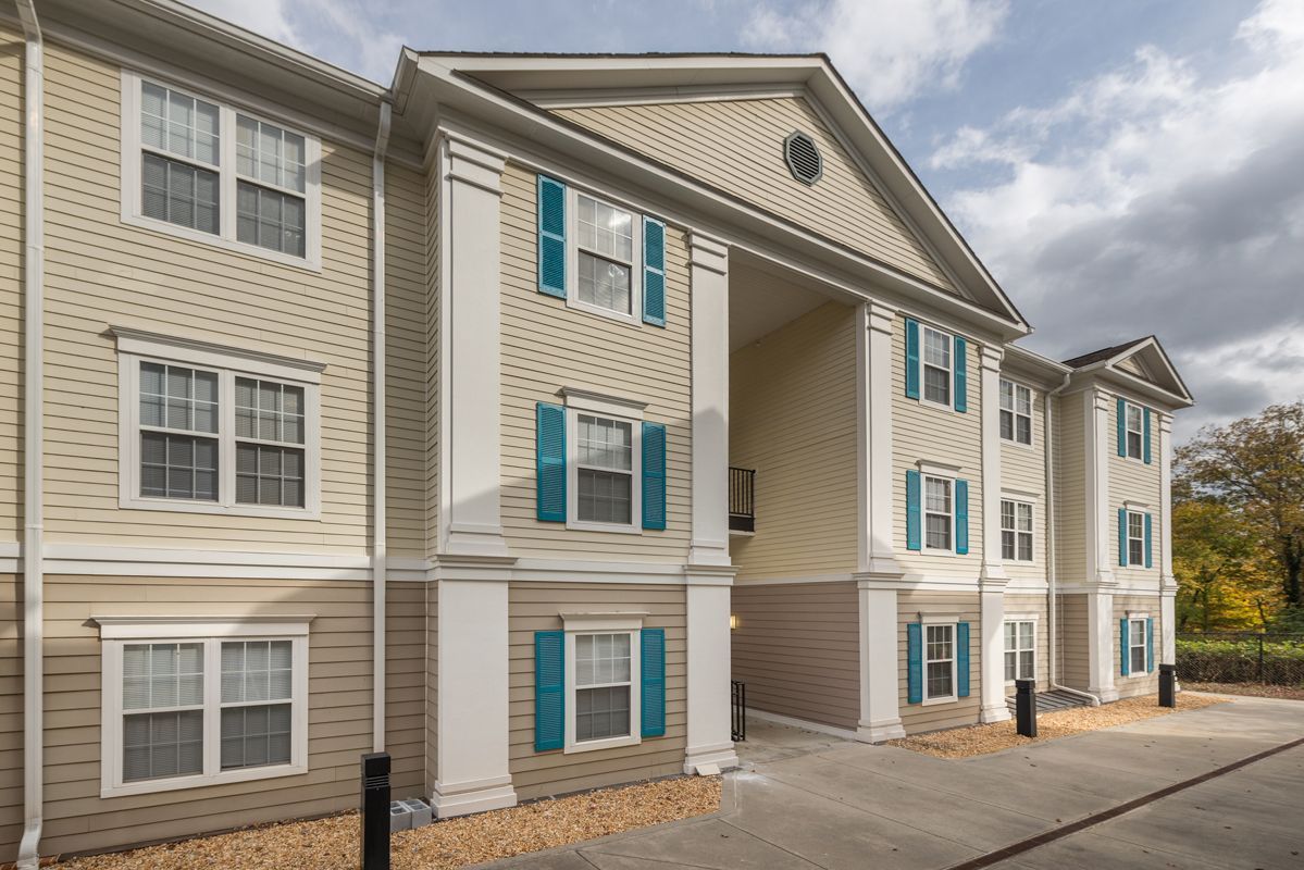 A large apartment building with a lot of windows and blue shutters.