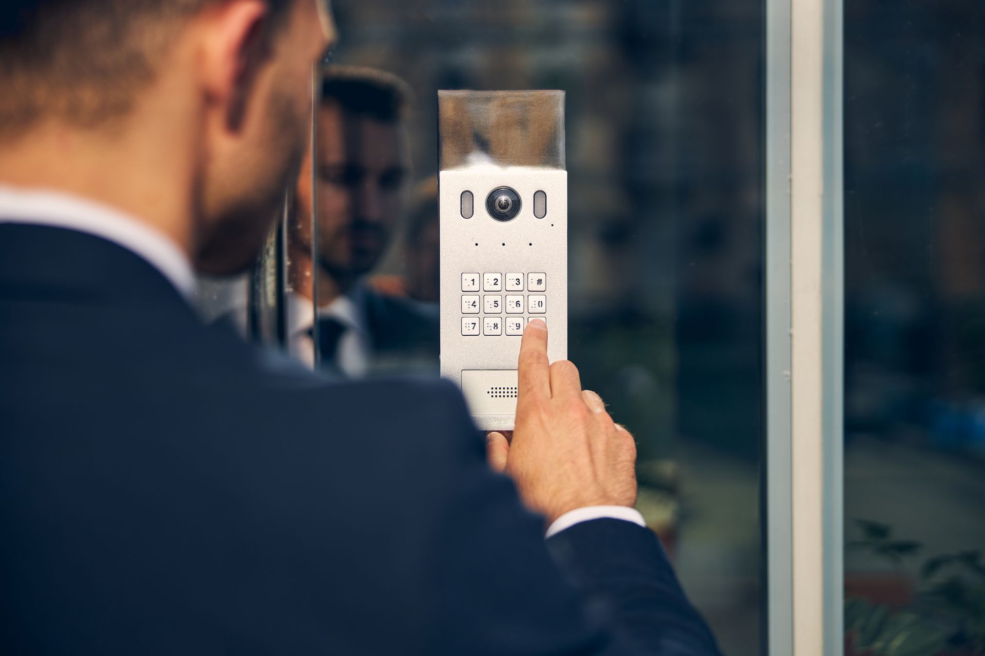 A man in a suit is pressing a button on a doorbell.