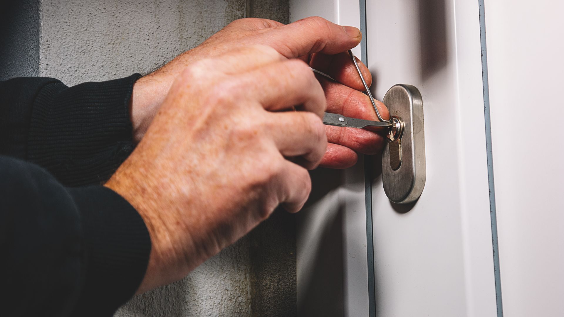 A man is using a screwdriver to open a door lock.