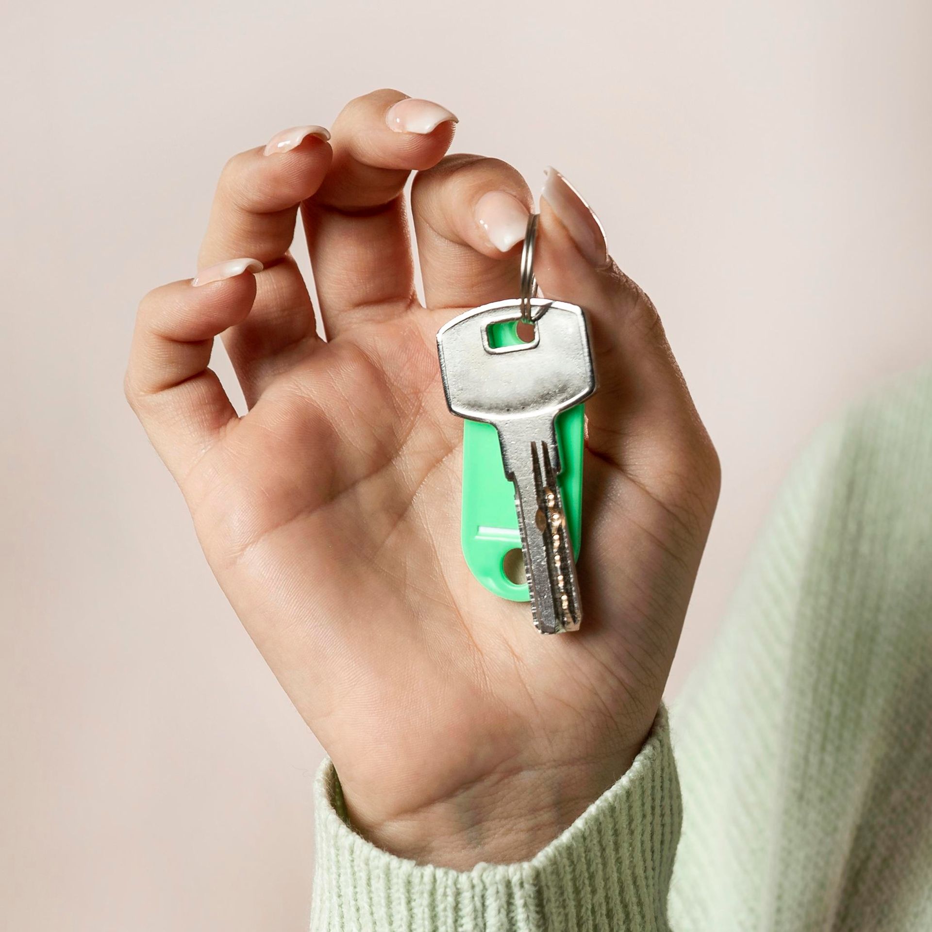 A person is holding a green key in their hand