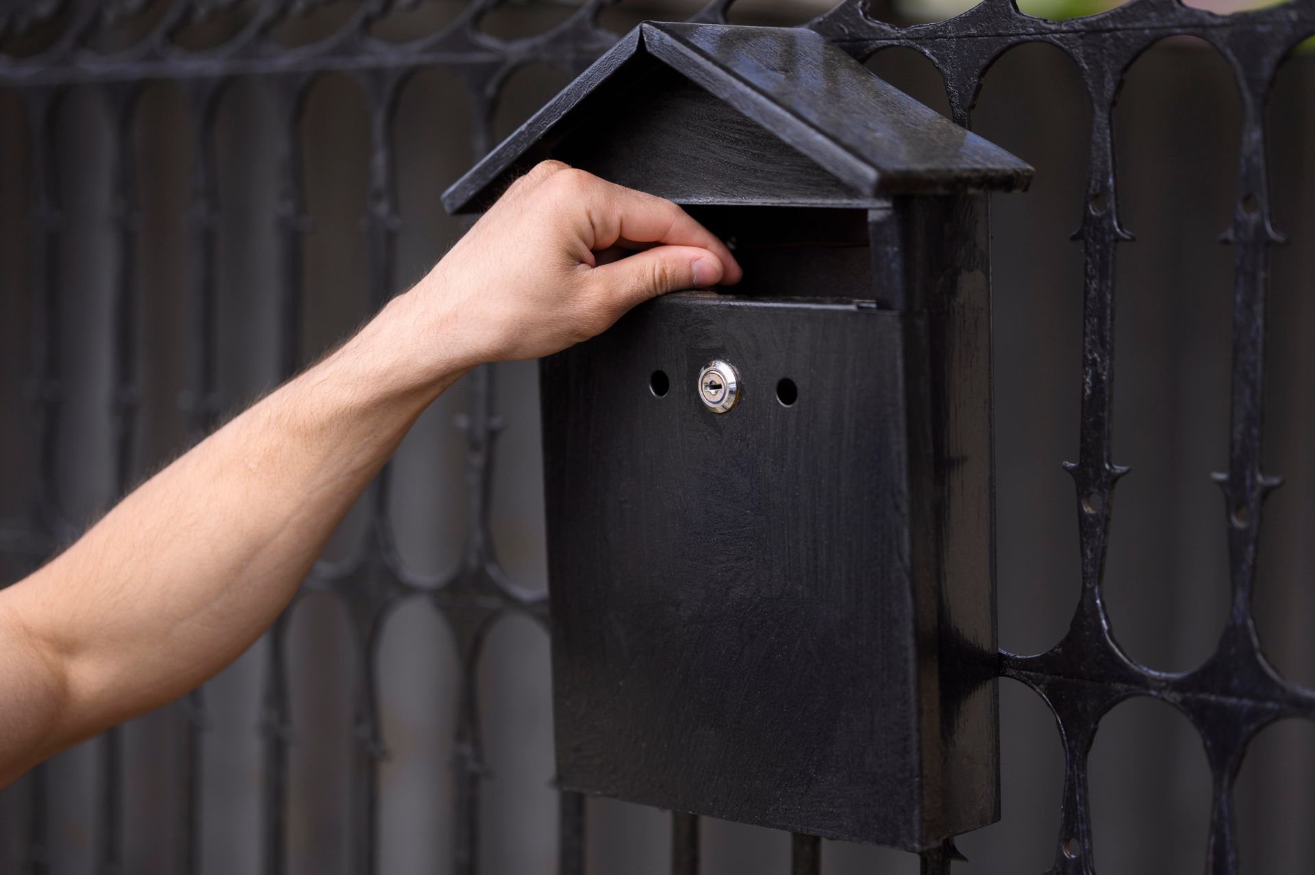 A person is putting a letter in a mailbox.