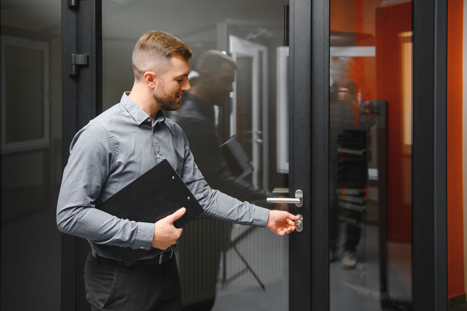 A man is opening a glass door with a key.