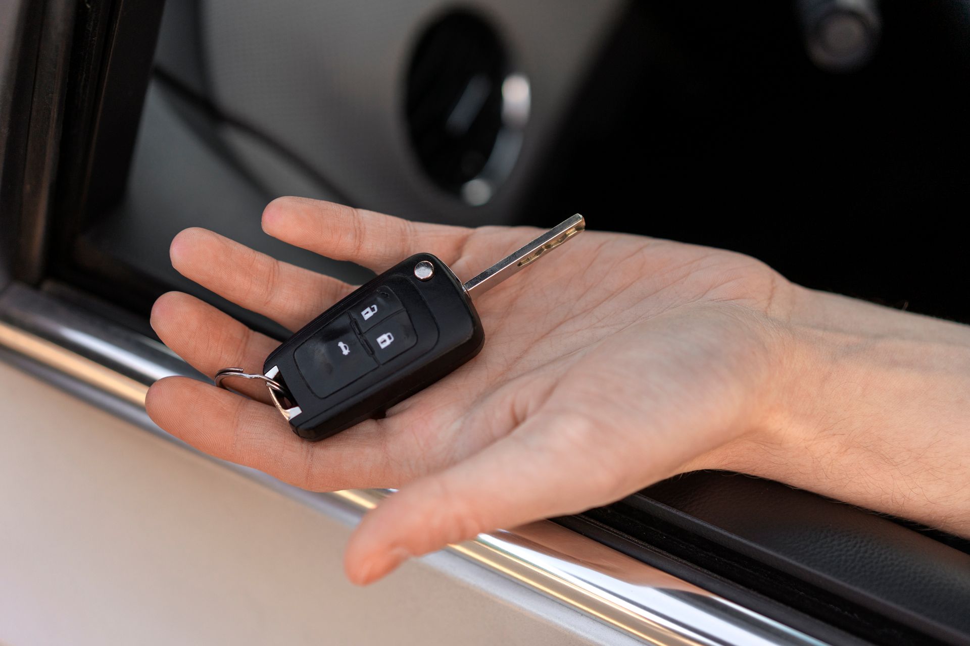 A person is holding a car key in their hand.