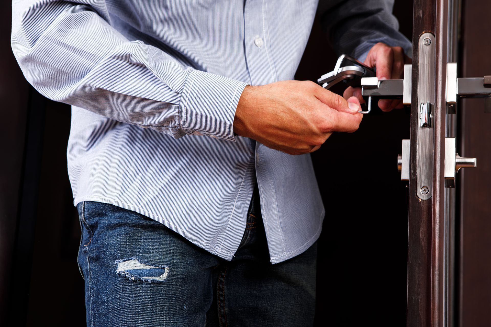 A man is fixing a door lock with a wrench.