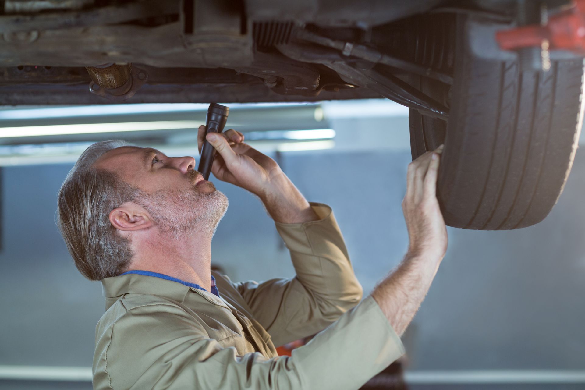 A man is working under a car in a garage.
