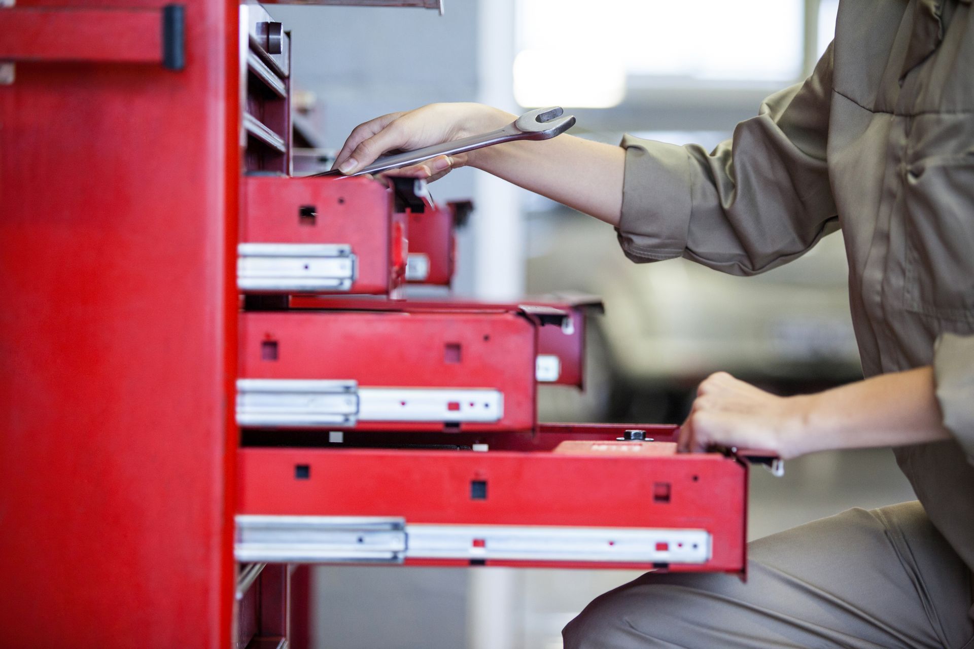 A man is using a wrench to open a red drawer.