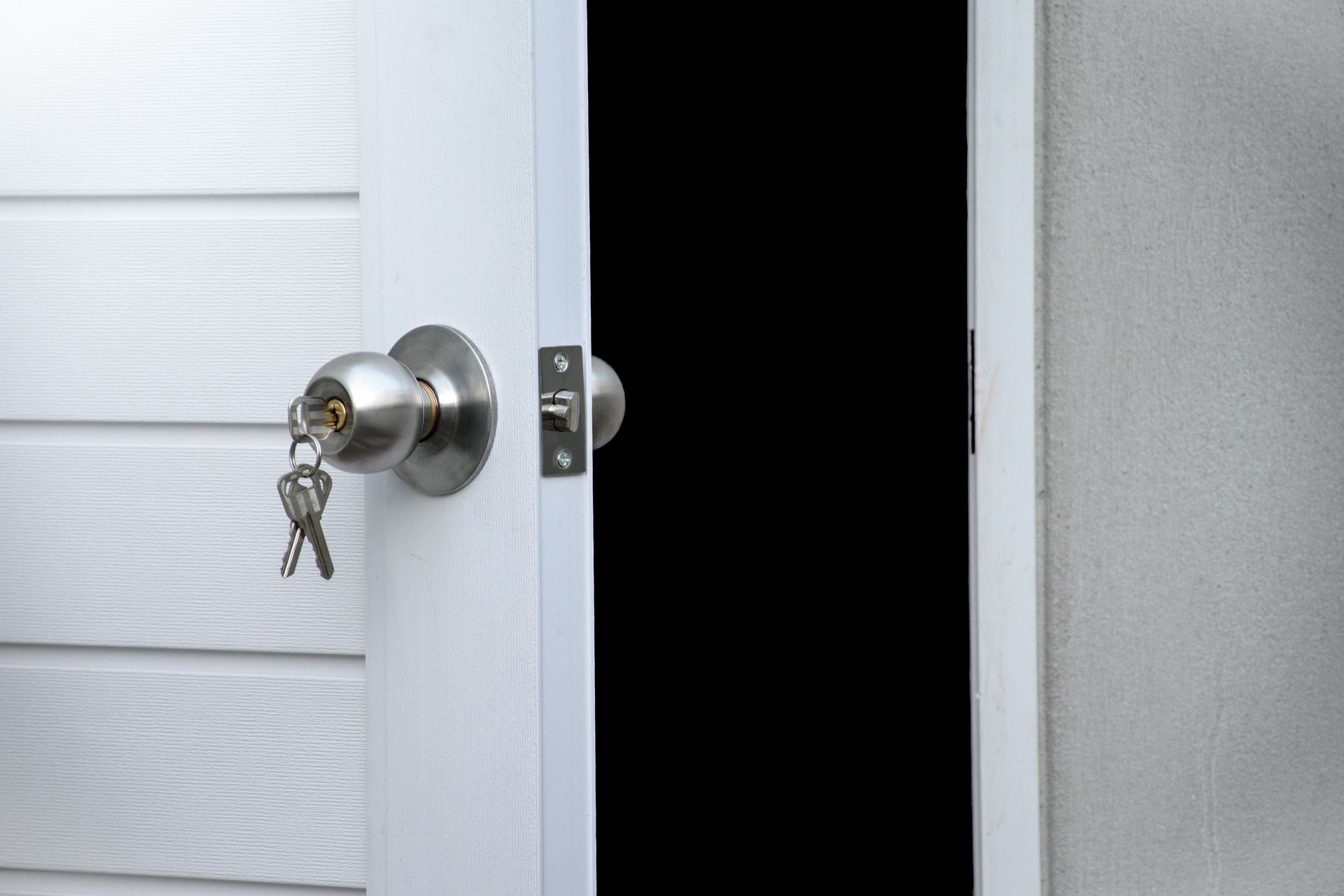 A close up of an open door with a key in the lock.