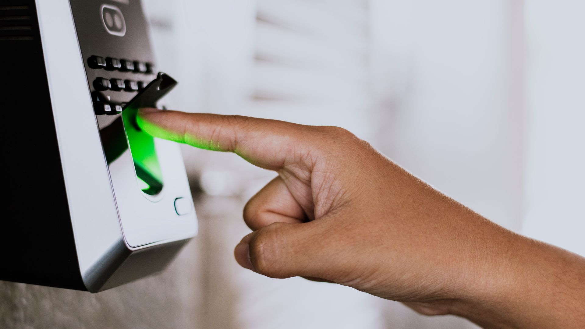 A person is pressing a green button on a fingerprint scanner.