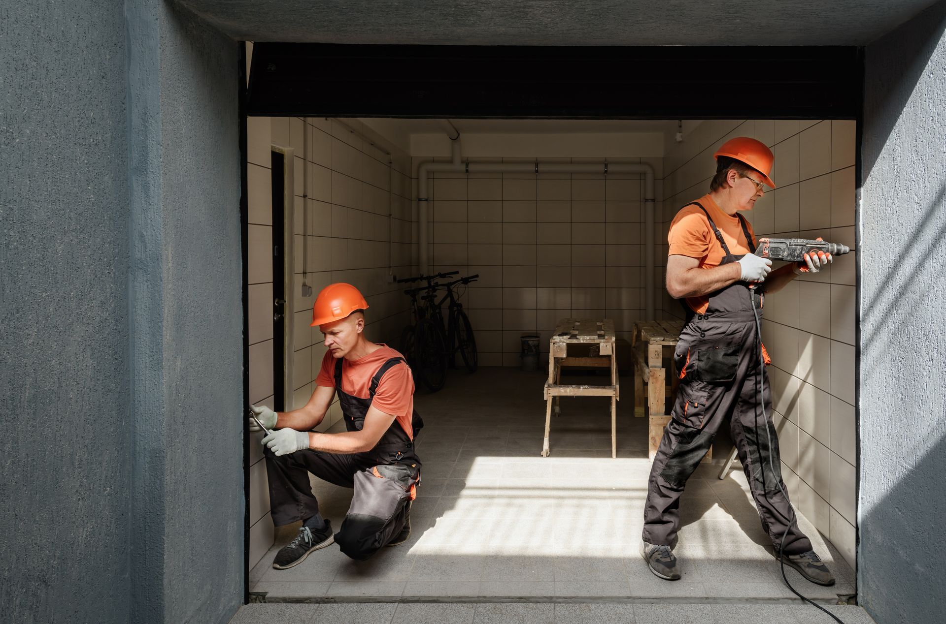 Two men are working on a garage door.